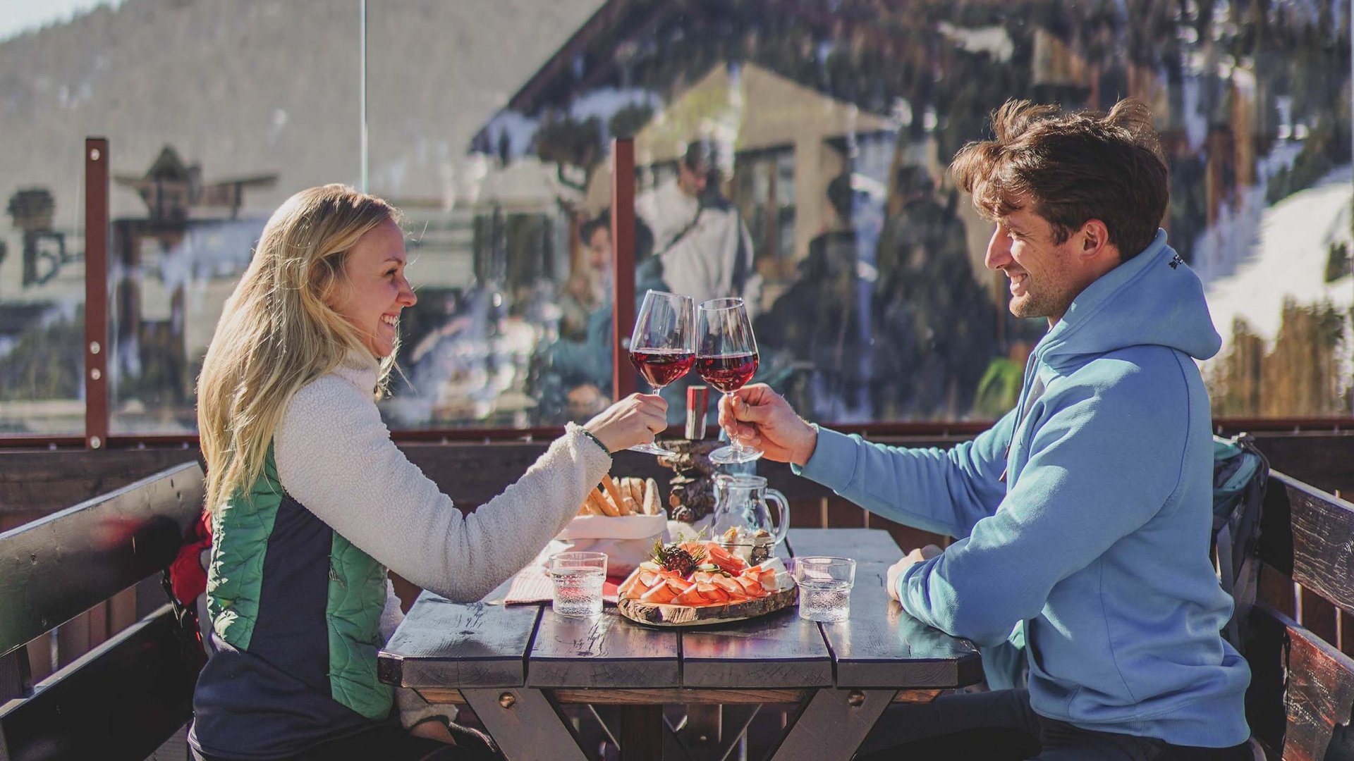 Coppia brinda con vino rosso su terrazza in ambiente montano